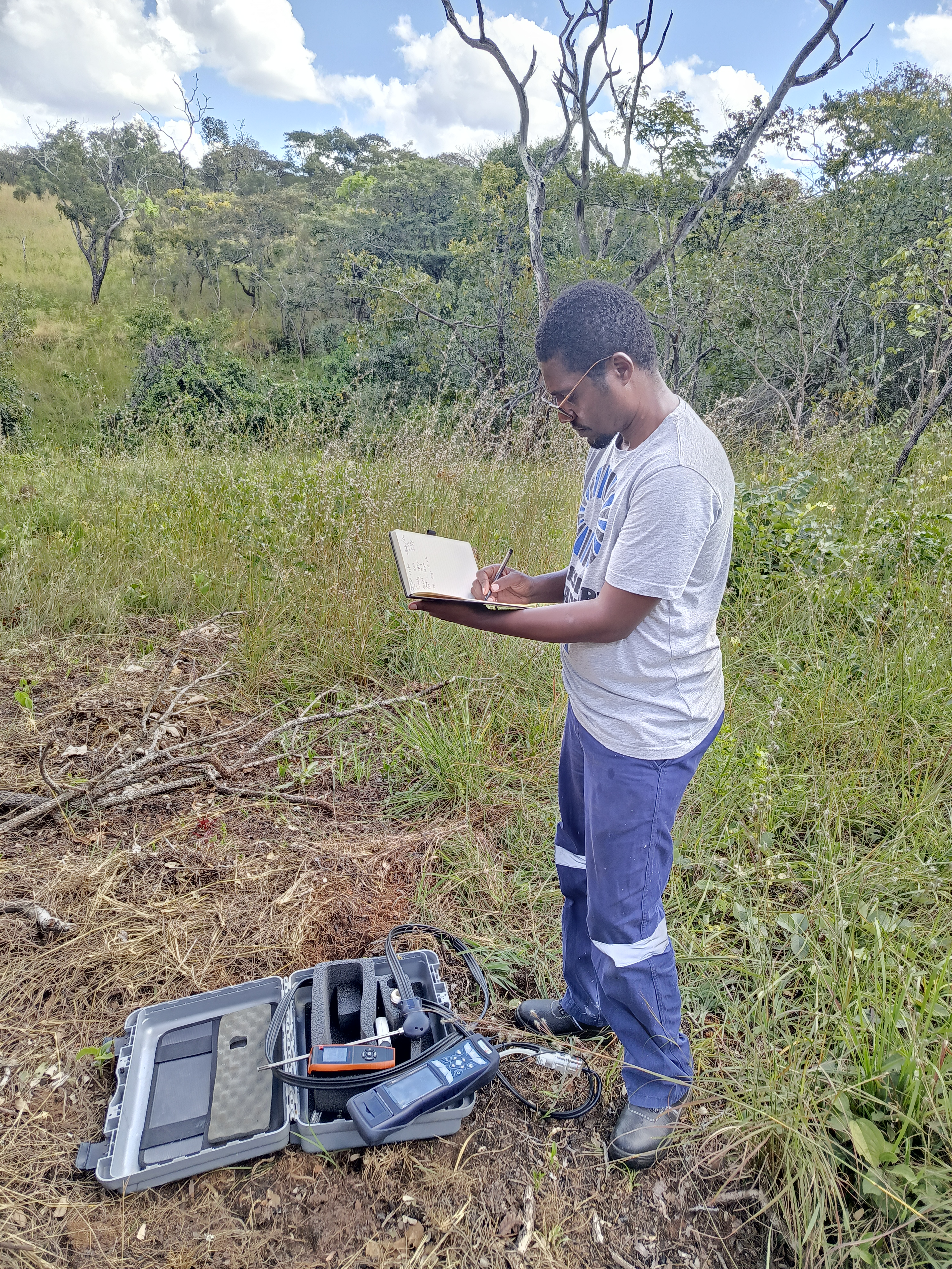 African agricultural specialists conducting sustainable farming assessment in Zambian terraced fields with monitoring equipment
